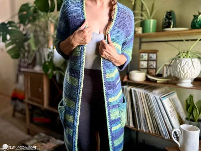 Female model wearing The Hedonist\'s House coat, in a green and blue colorway.