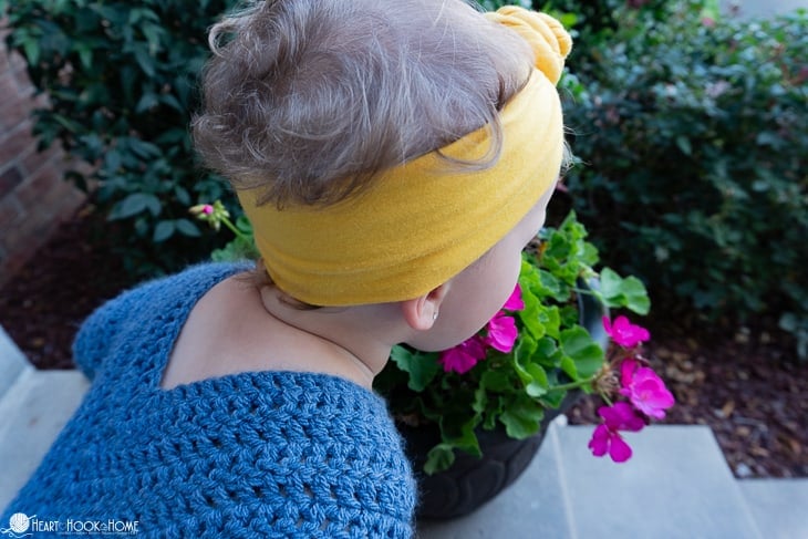 Blue example of the 2/3T size of the On Point Poncho crochet pattern on a small child in a backyard setting.
