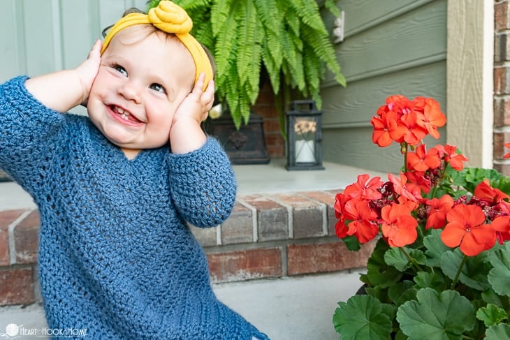 Blue example of the 2/3T size of the On Point Poncho crochet pattern on a small child in a front yard setting.