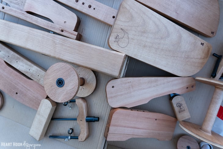 Unfinished and unassembled spinning wheel parts sitting in a box.