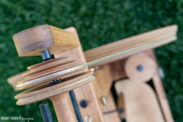 Up close of a spinning wheel sitting on grass.