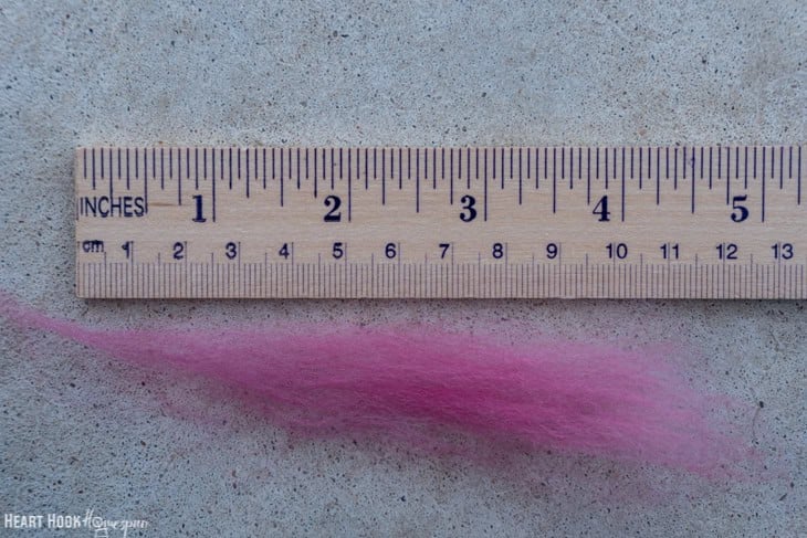Pink roving yarn under a ruler.