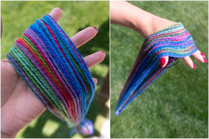 A hand holding multi colored yarn testing how well the yarn is balanced by letting it hang. 
