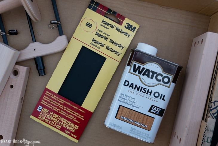 Sandpaper, Danish Oil, and an unassembled and unfinished spinning wheel.