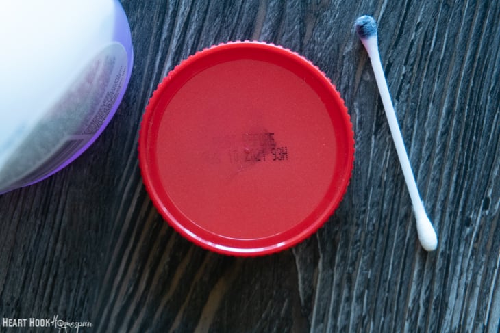 Acetone nail polish remover being used to remove the date from the top of a beef bullion container.