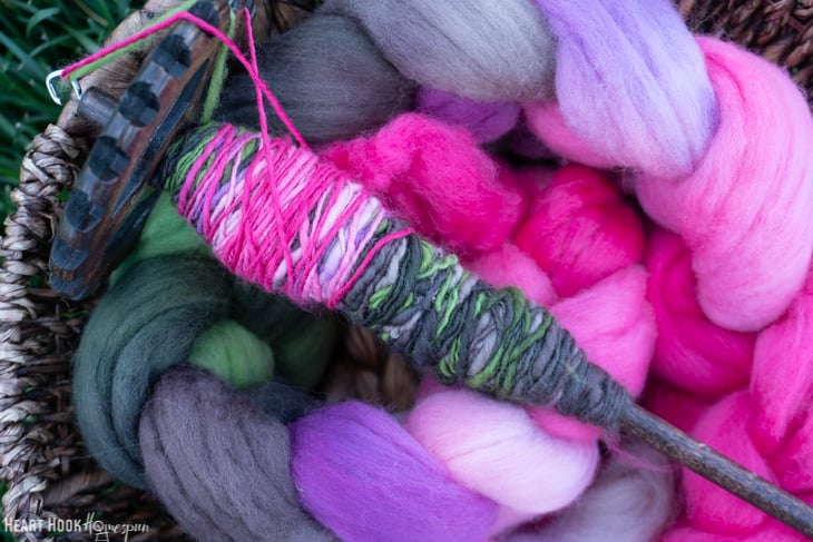 Example of a first attempt of handspun yarn on a drop spindle sitting on roving yarn.