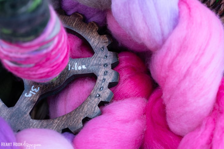 Drop Spindle sitting on pink roving yarn.