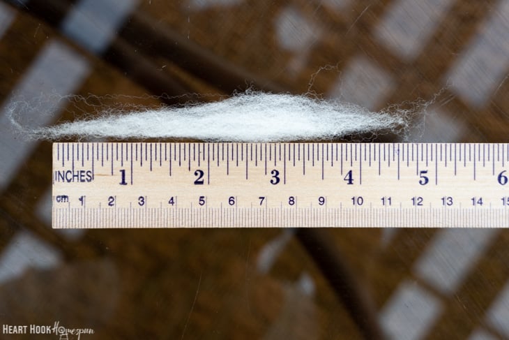 White roving yarn next to a ruler.