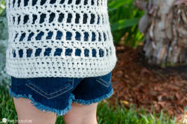 Back of a white example of the Child Size Cold Shoulder Coverup crochet pattern on a child wearing jean shorts.