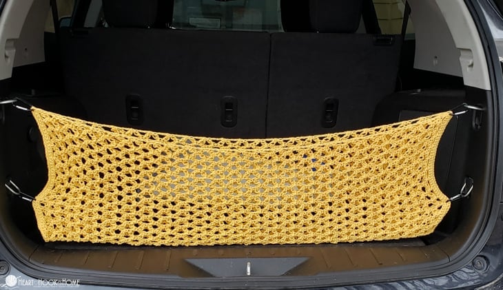 Example of a yellow version of a Trunk Cargo Net crochet pattern installed inside of a vehicle.
