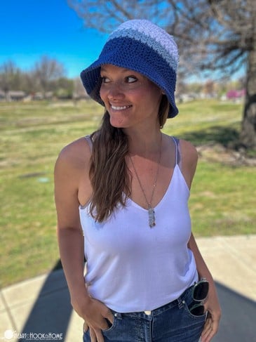 The Sports Team Bucket Hat in Kansas City Royals colors on a smiling female model wearing a white tank top in a sunny park setting.