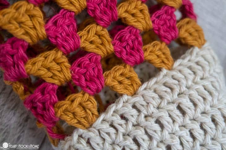 Up close of a sample of the Granny Stitch Water Bottle Holder crochet pattern in a gold, pink, and cream colorway.