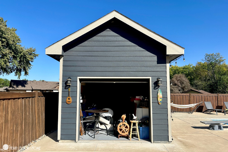 Tall blue-gray shed with white trim and filled with odds and ends.