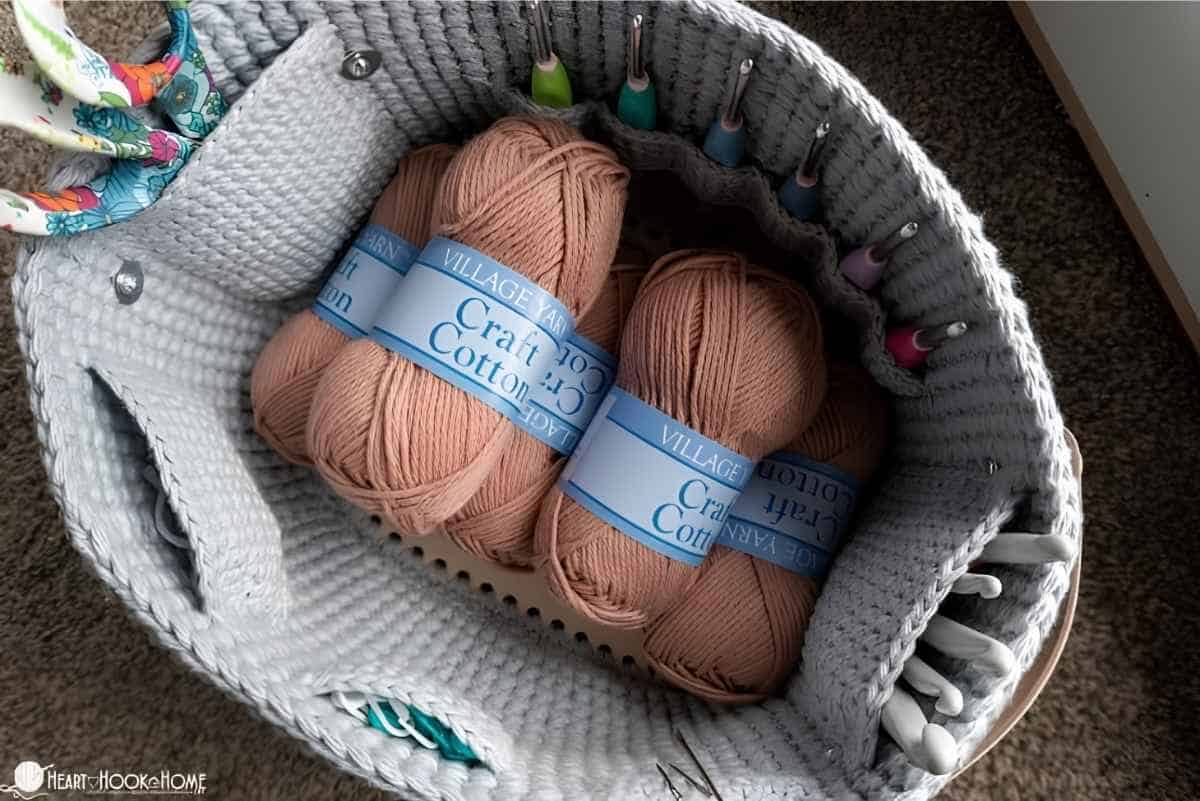 A crocheted yarn organizer / fanny pack filled with crochet supplies.